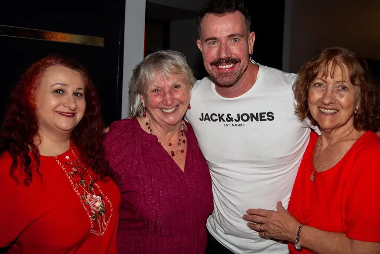 A visiting guest posing with club members at an indoor social.